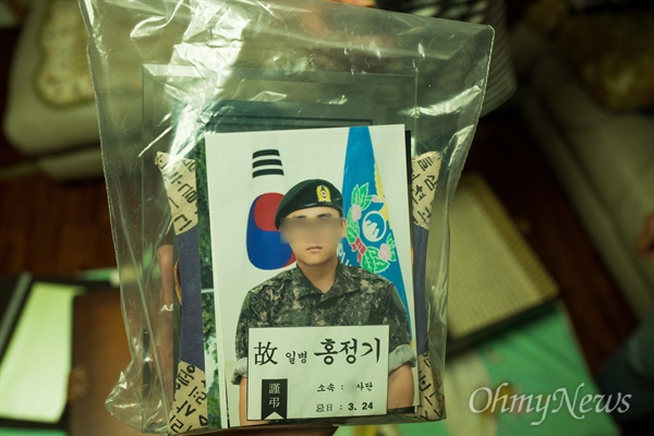 고 홍정기 일병의 군입대 사진과 유품이 비닐팩에 보관되어 있다.