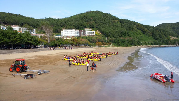 백사장에서는 래프팅을 준비하고 있고, 왼쪽 솔숲 안에서는 인명 구조법에 대한 이론수업이 한창이다.