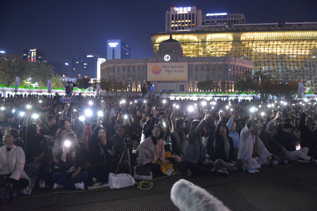 큰 함성 소리와 함게 핸드폰 불빛을 켜고 '전쟁 반대'와 '한반도 평화'를 외치는 청년들.