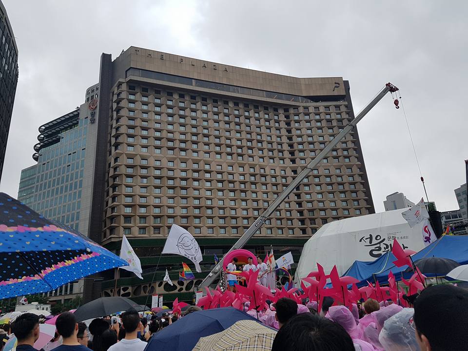 서울에서 열린 제18회 퀴어문화축제에서 행진을 기다리던 중이다. 주최측 추산 5만 명의 참가자가 모였다. 행진할 때 선두에 서는 트럭별로 다른 음악을 트는데, '러시' 트럭이 인기가 많다. 반대 진영의 참가자가 이 트럭 앞에 드러눕기도 했다.