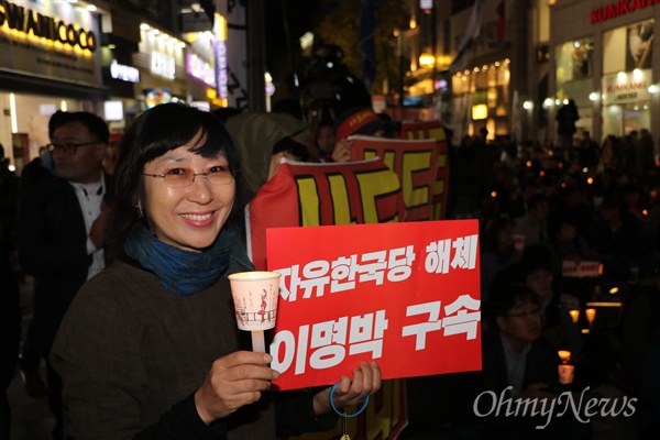 4일 오후 대구백화점 앞에서 열린 '촛불 1년'을 기념하는 집회에서 한 시민이 촛불과 '자유한국당 해체, 이명박 구속'이라고 쓴 피켓을 들고 있다.