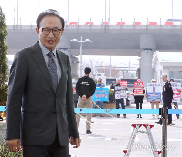 "다스는 누구겁니까" MB 출국 인천공항 시위  이명박 전 대통령이 중동으로 출국하기 위해 12일 인천공항에 도착하고 있다. 뒤로 "다스는 누구겁니까" "MB구속 적폐청산" 등의 피켓을 들고 시위를 벌이는 시민들이 보인다. 