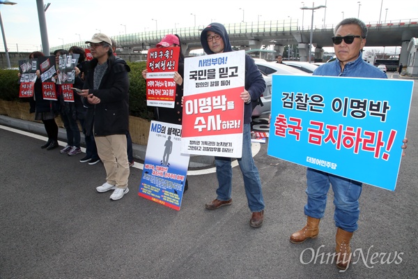 이명박 전 대통령이 중동으로 출국하기 위해 12일 인천공항에 도착한 가운데, 시민들이 "MB 출국 금지하라" "다스는 누구겁니까" "MB구속 적폐청산" 등의 피켓을 들고 시위를 벌이고 있다.