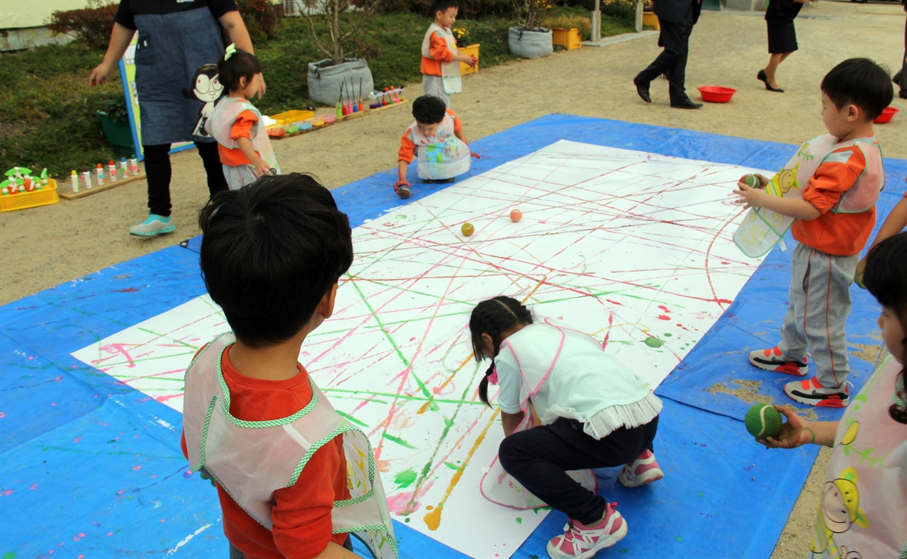 만 3세)반 아이들이이 큰 전지 위에 다양한 색깔의 물감을 묻힌 공을 굴리는 놀이를 하고 있다.