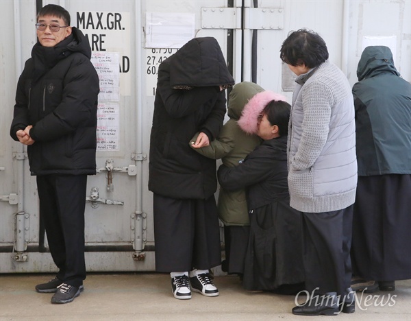 상복 입기엔 너무 어린 아홉살 세월호 미수습자 권재근씨의 딸(9세)이 검은 상복을 입고 18일 오전 목포신항 세월호 선체 선수부 인근 안치실에서 '시신 없는' 입관식을 지켜본뒤 남은 가족들의 품에 안겨 있다. 