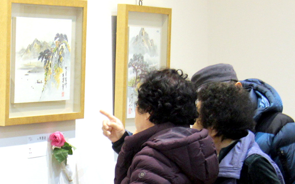 회원들이 전시장을 찾은 가족들에게 작품 설명을 하고 있다.