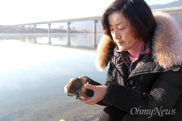 한은정 창원시의원이 11월 26일 낙동강 합천창녕보 상류에서 죽은 조개를 발견해 살펴보고 있다.