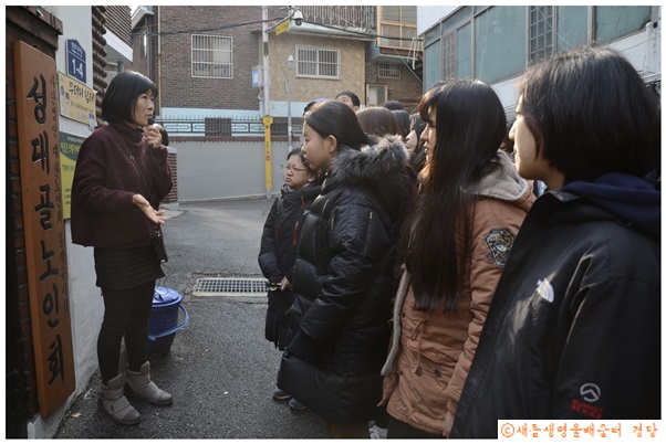 단열 공사를 한 경로당 앞에서 설명을 듣고 있는 학생들