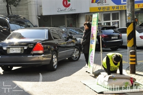 2012년 10월 31일 절을 하고 있는 박문진씨 옆으로 박근혜 당시 대선후보가 탄 차량이 지나치고 있다. (뉴스민 자료사진)