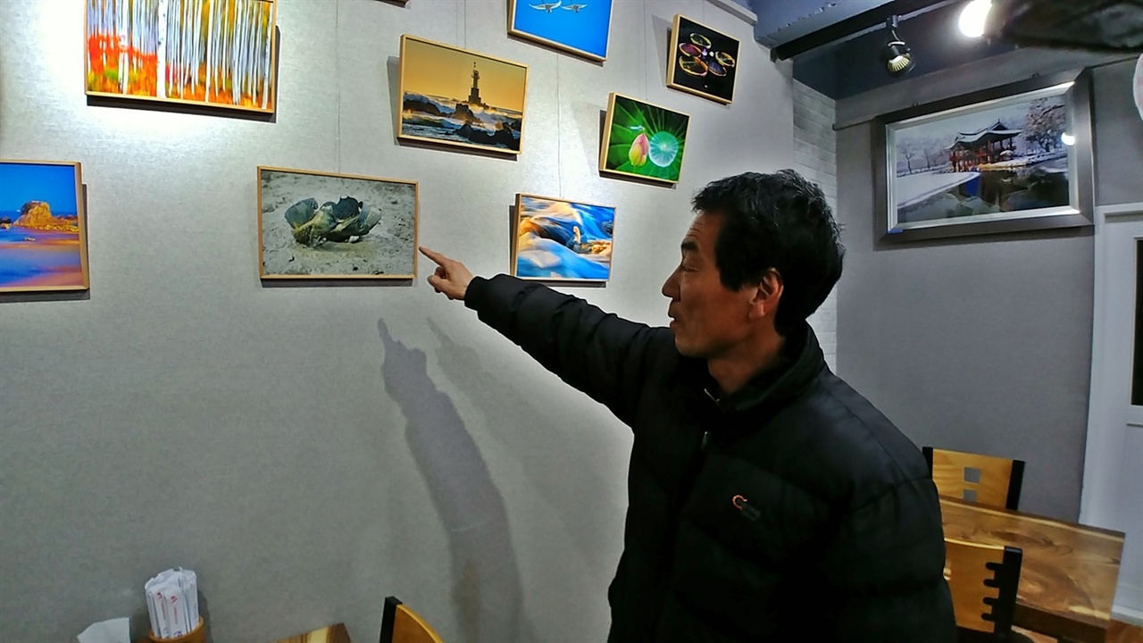 여수 덕양 진남반점의 주인장이 자신의 사진 작품을 설명하고 있다. 
