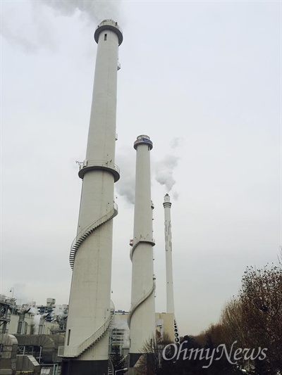 연기가 나오지 않는 한 개의 굴뚝, 그 위에 노동자들이 있다.
