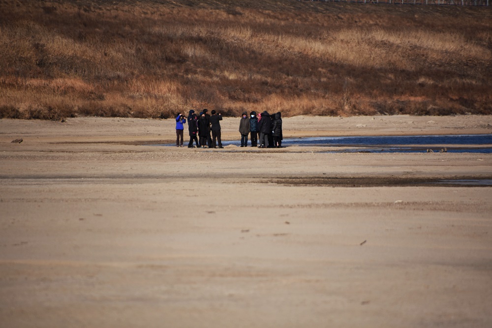 낙동강 네트워크 소속 단체 회원들이 낙동강으로 걸어들어가, 되돌아 온 모래톱 위를 밟아보고 있다.   