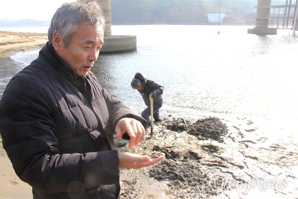  대한하천학회와 경남환경운동연합, 낙동강네트워크가 16일 낙동강에서 '정부의 수문 개방 이후 낙동강 환경 변화 모니터링'을 한 가운데, 박창근 가톨릭관동대 교수가 합천창녕보 상류에 있는 율지교 부근에서 땅 속 깊이에서 파낸 모래를 살펴보고 있다.