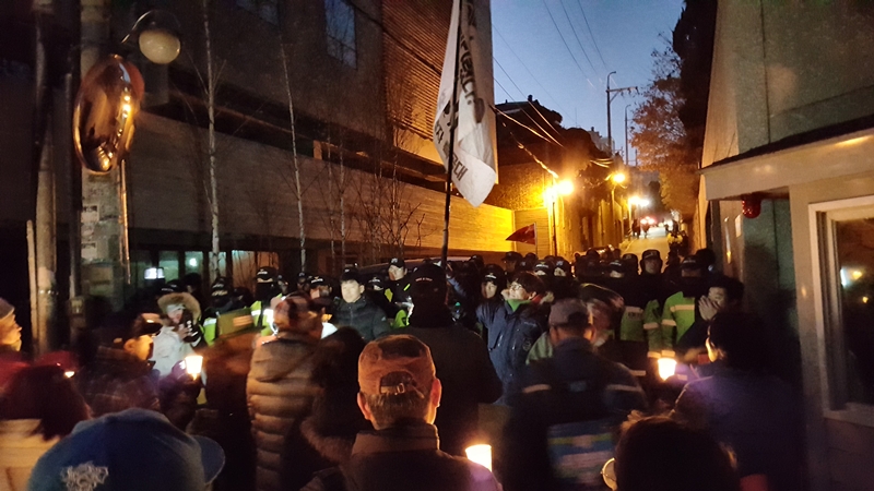 16일 오후 서울 강남구 학동역 인근에서 열린 '명박산성 허물기 촛불난장 문화제'에 참석한 사람들과 경찰이 이명박 전 대통령 자택 앞에서 마주 서 있다. 