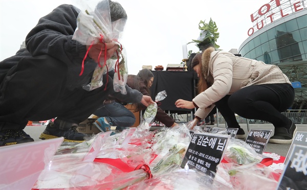 지난해 12월 21일 서울역광장에서 열린 홈리스추모제에서 관계자들이 홈리스, 무연고 사망자들 이름위에 추모의 꽃을 놓고 있다.