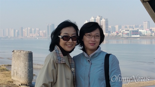 '조중친선다리'에서 안내원 경미와 함께. 사진 왼쪽 하단이 한국전쟁 때 파괴된 압록강철교의 잔해다. 그리고 압록강 건너 보이는 건물들은 중국의 단둥시다.