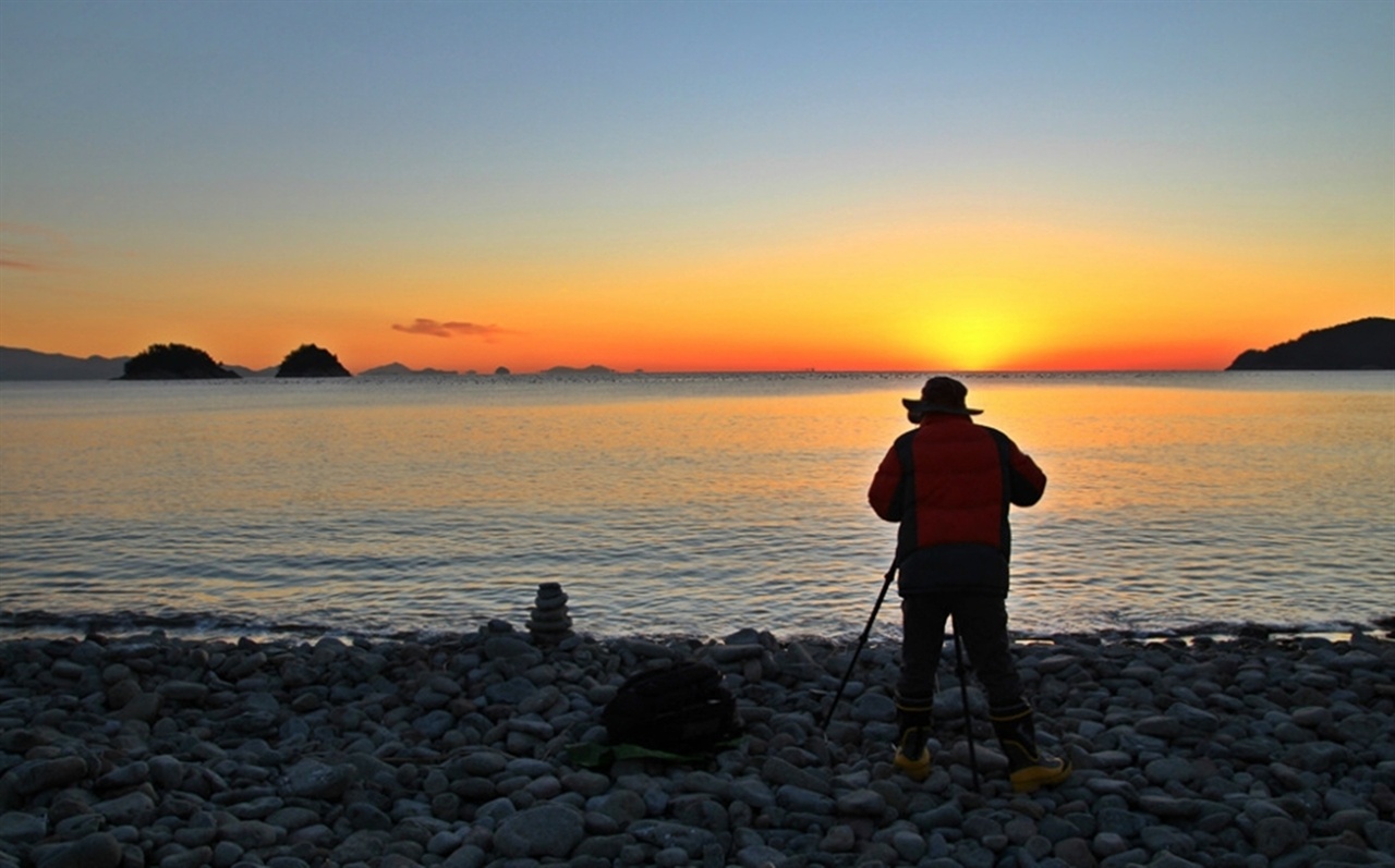 한 사진작가가 무슬목에 떠오르는 태양을 카메라에 담고 있다. 왼편에 보이는 두 개의 섬이 형제섬이다.

