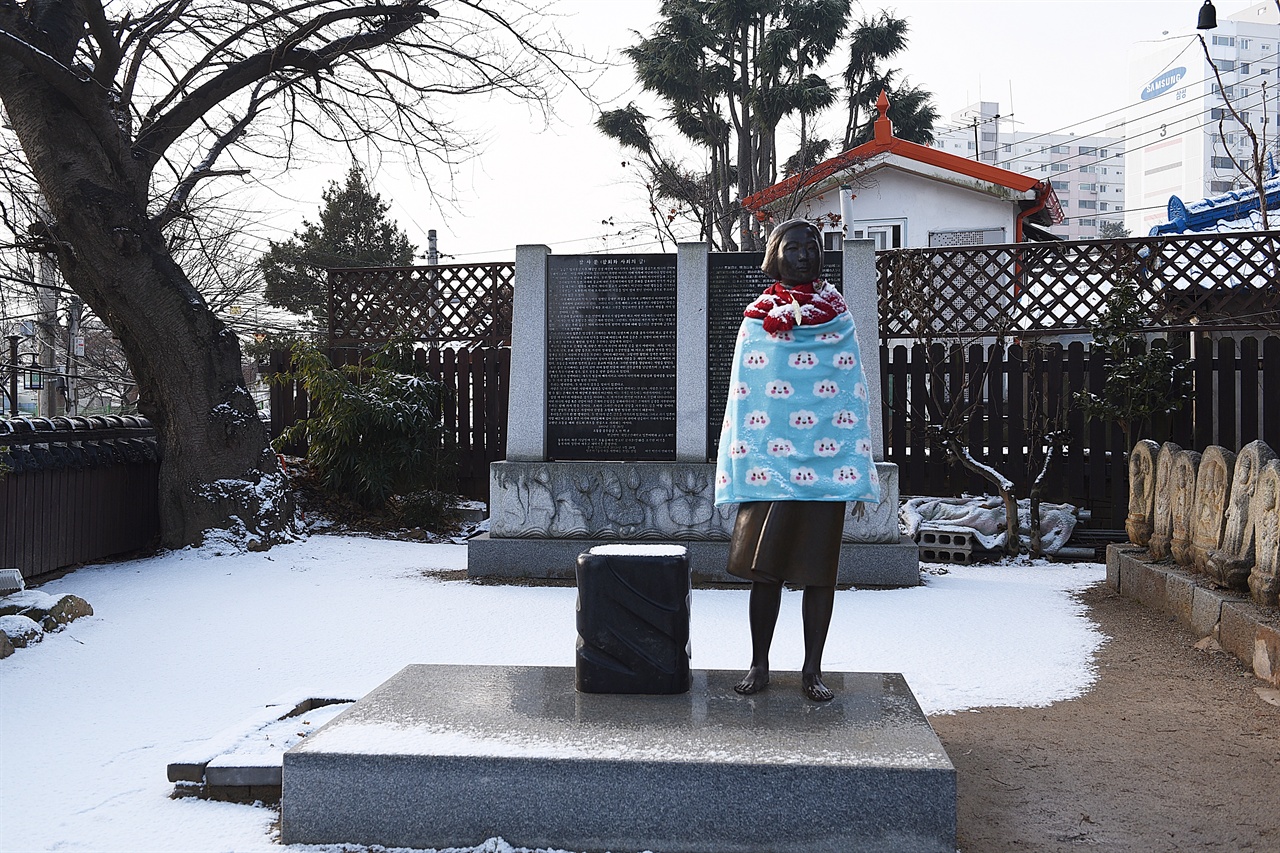 눈 내린 겨울 아침, 동국사 서쪽편에 당당하게 서 있는 소녀상. 뒤에 참사비가 있다