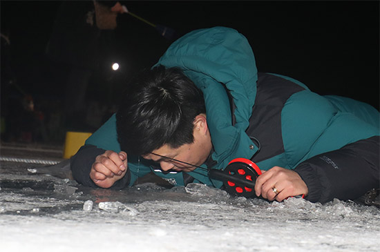 밤 낚시 중인 관광객 개막 첫 날인 6일과 7일 야간에는 산천어 밤낚시 장에는 많은 관광객들이 몰려 얼음 구멍속을 들여다 보며 낚시에 열중하고 있다.