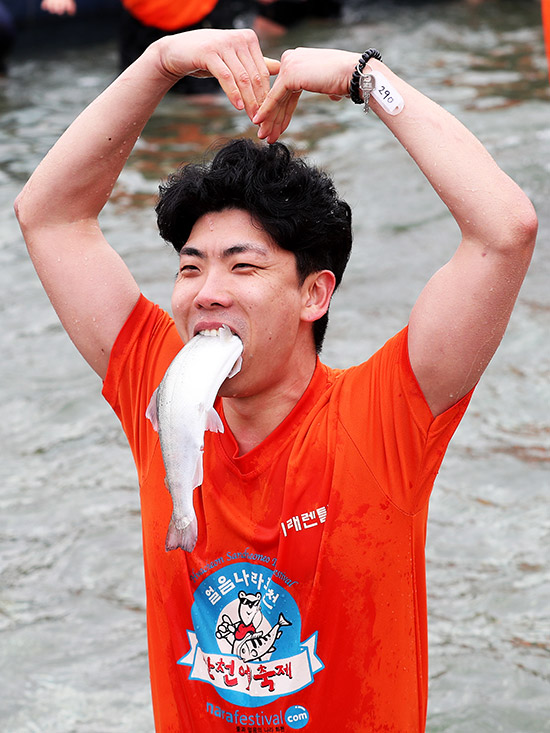 8일 화천산천어축제장 산천어맨손잡기 체험에 참가한 관광객이 맨손으로 잡은 산천어를 입에 물고 즐거워하고 있는 모습