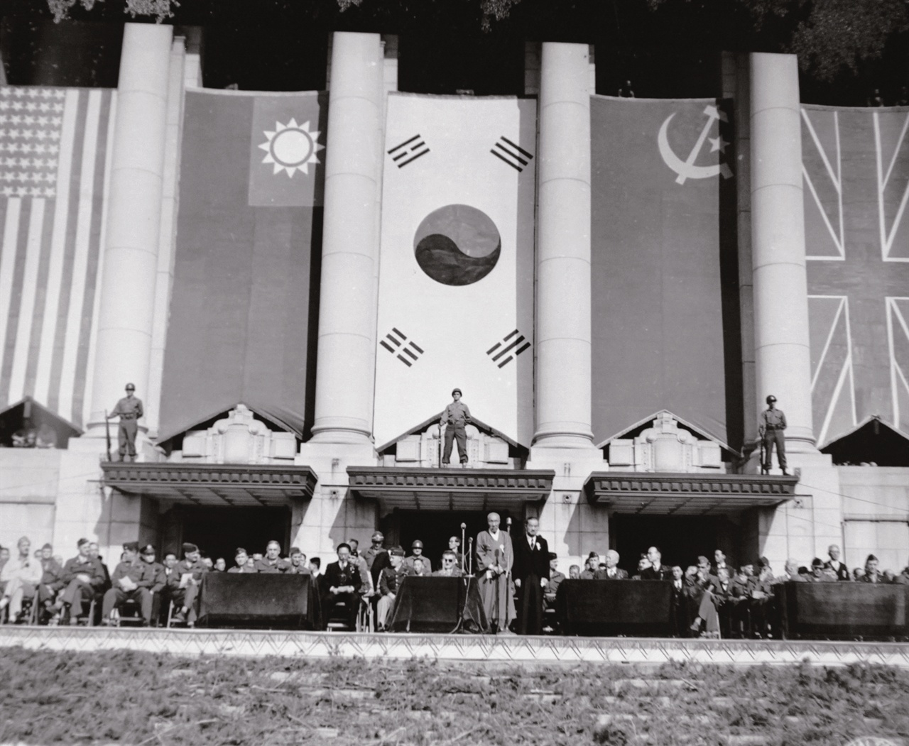 연합군 환영대회에 참석한 조선인과 연합군 고위 장교단(1945. 10. 20.)
단상 위 인사들 머리 위에 무장 경계병이 이채롭다.