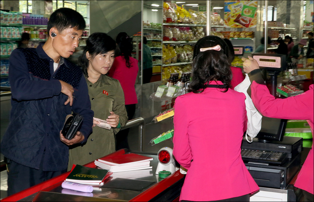  광복백화점에서 물건을 사는 북한 주민의 모습. 남성의 귀에 '블루투스 이어폰'이 끼워져 있다. 진천규 기자는 "사진을 찍을 때는 몰랐는데, 찍고 나서 사진을 확인하면서 발견했다"고 밝혔다.