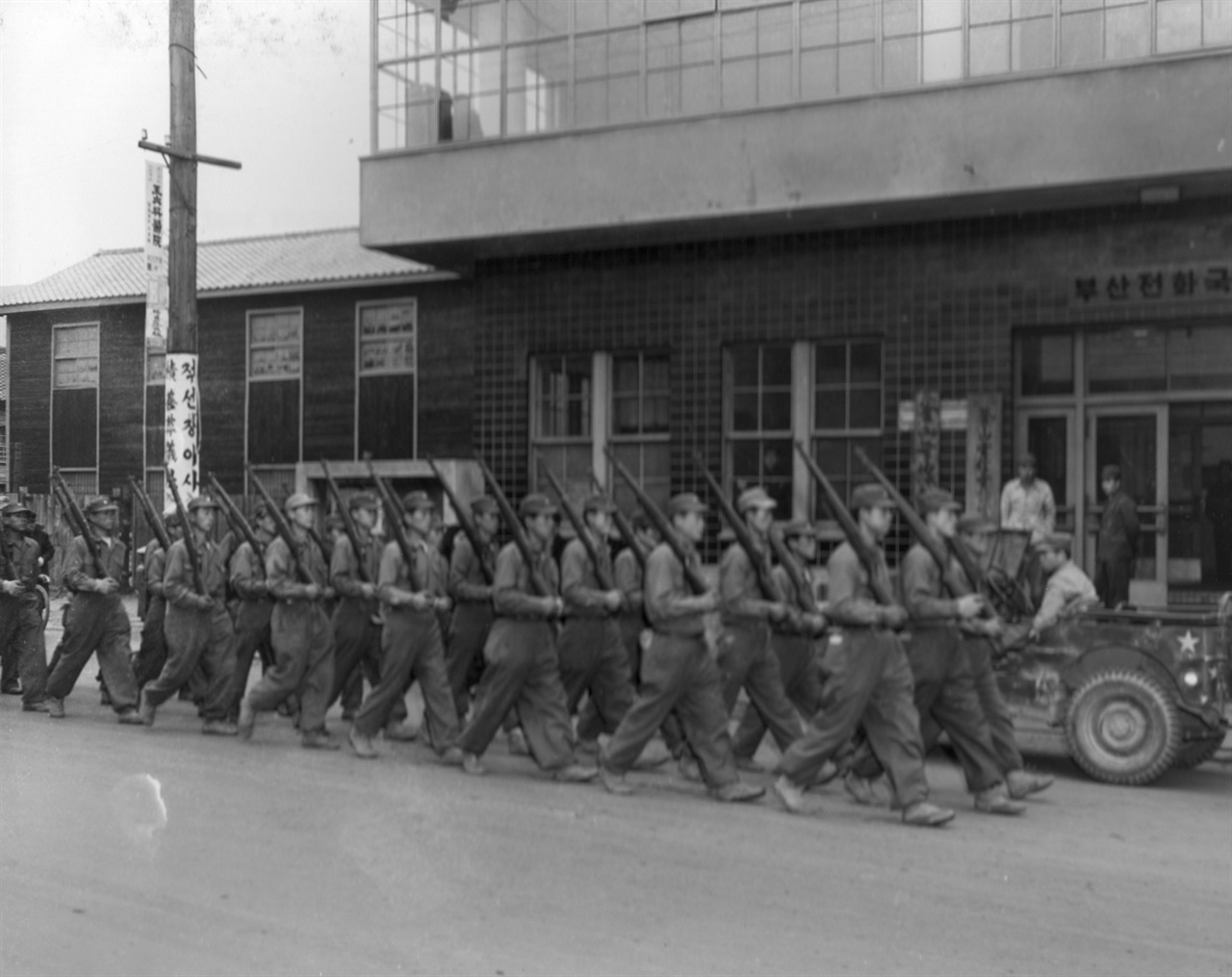  1951. 1. 8. 부산, 훈련병들이 우로 어깨 총 자세로 부산전화국 앞을 지나고 있다.