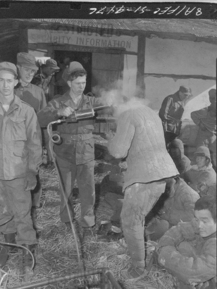 1951. 5. 10. 유엔군이 중국군 포로에게 분무기로 DDT를 뿌리고 있다.