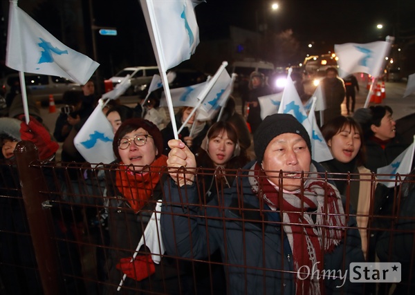 공연장 밖에서 북측 예술단 기다리는 시민들 "우리는 하나다"  8일 오후 강원도 강릉 아트센터에서 열린 북측 삼지연관현악단 공연이 성황리에 끝나자, 공연 관람에 당첨되지 않아 밖에서 북측 예술단을 기다리는 시민들이 한반도기를 흔들며 “우리는 하나다”를 외치고 있다.
