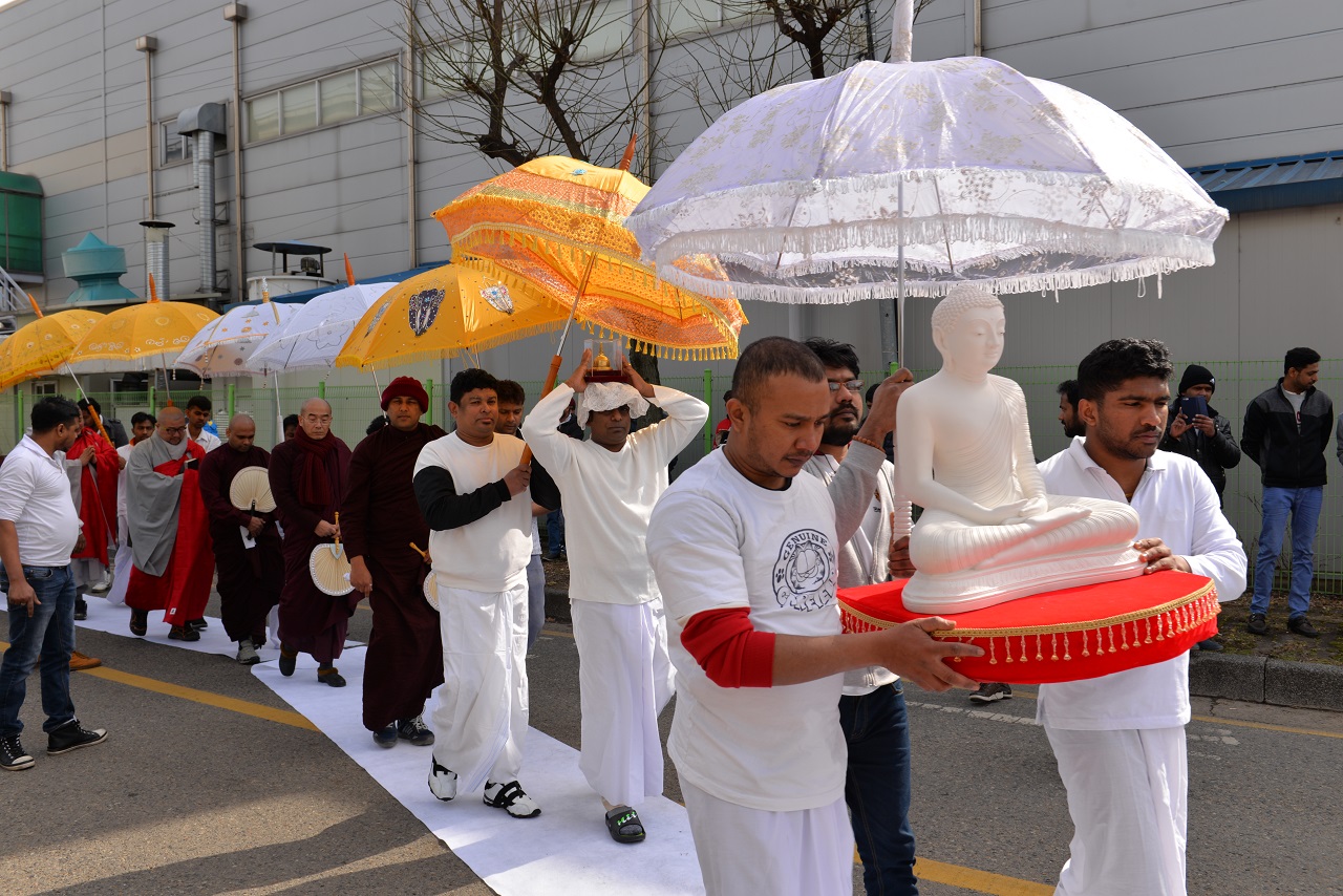 스리랑카 이주노동자들이 스리랑카 국기와 불교도기를 앞세우고 전통악기를 연주하며 부처님과 스님들을 모시고 있다. 길에는 흰 천을 깔아 부처님과 스님들이 땅을 밟지 않게하고 일산을 들어 햋빚을 막는 최고의 경의를 표하고 있다.