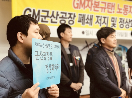 한국지엠 군산공장 폐쇄 저지 대책위 기자회견에 한 활동가가 피켓을 들고 있다.