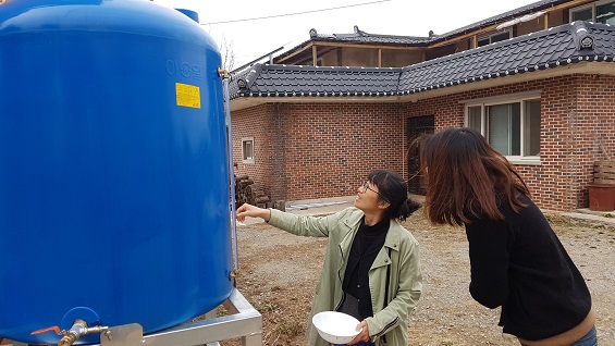  신은미 예산홍성환경운동연합 간사가 빗물저장소의 눈금을 바라 보고 있다. 빗물저장소 눈금은 1000리터를 가르키고 있다. 