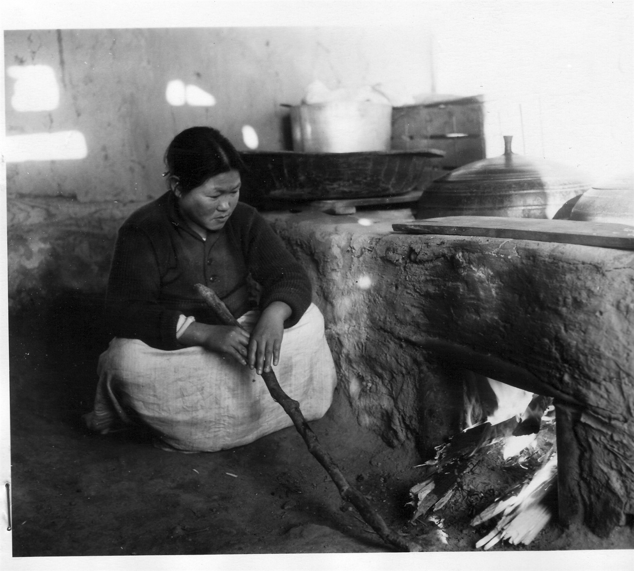 1952. 11. 18. 아낙네가 시골집에서 저녁밥을 짓고자 아궁이에 장작불을 때고 있다.