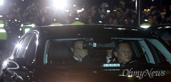 뇌물수수 등 혐의로 구속영장이 발부된 이명박 전 대통령이 23일 오전 검찰 차량을 타고 서울동부구치소로 들어가고 있다. 이 모습을 지켜보는 시민들이 박수를 치거나 폰카를 찍고 있다.