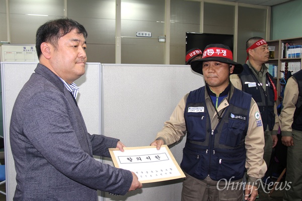  고민철 전국금속노동조합 STX조선지회장이 27일 오후 더불어민주당 경남도당을 찾아 정경원 사무처장한테 항의서한을 전달하고 있다.