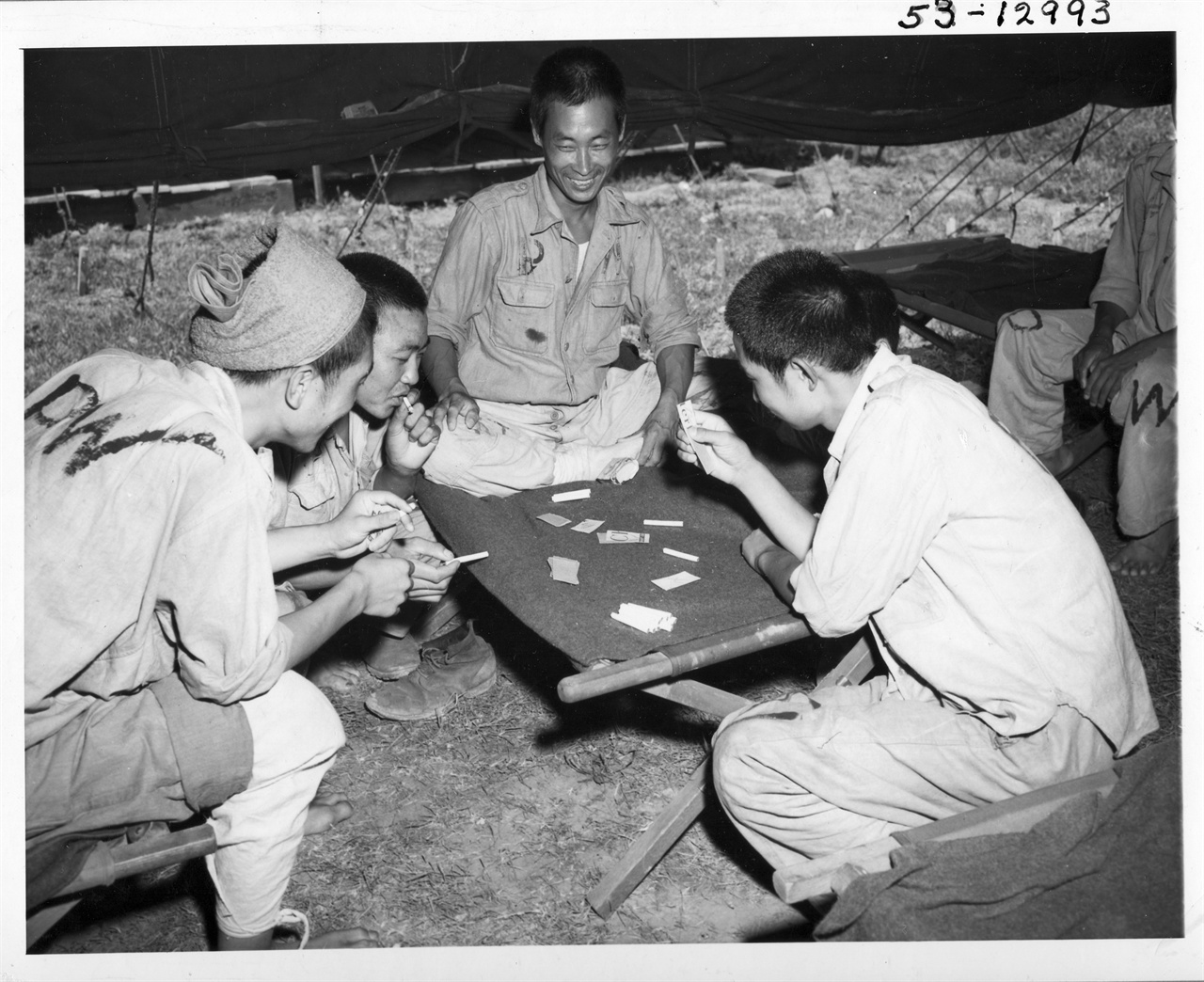 1950. 8. 28. 임시 포로수용소 막사에서 포로들이 담배껍질로 만든 카드로 담배내기 게임을 하고 있다.