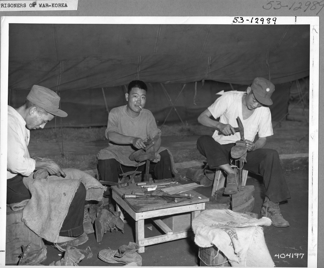 1952. 7. 거제도, 포로수용소에서 포로들이 신발을 수선하고 있다.