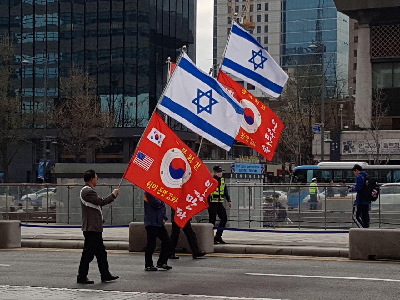 2018년 4월, 집회 참가자들이 태극기와 성조기 그리고 이스라엘 국기가 그려진 깃발을 들고 행진하고 있다. 