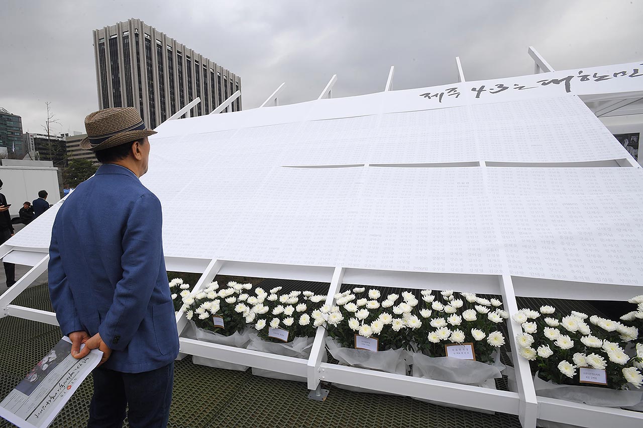 제주 4.3 70주년 광화문 추념식이 3일 오전 서울시 종로구 광화문광장에서 열리고 있는 가운데 한 추모객이 당시 희생자들의 이름을 확인하고 있다. 2018.04.03