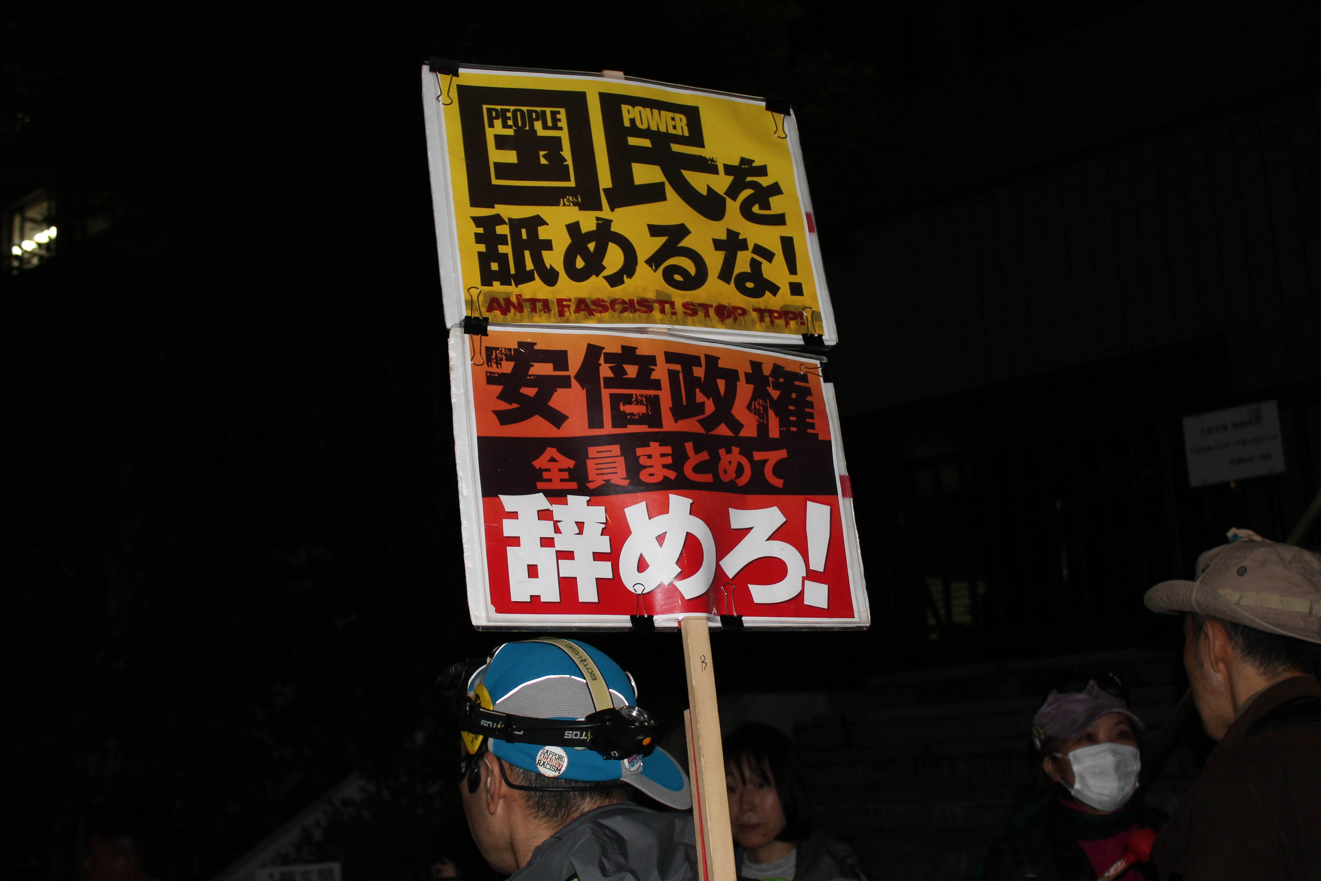 6일 저녁 도쿄 치요다구 일본 총리 관저앞 시위에서 한 참가자가 '국민을 깔보지 말라', '아베 정권은 퇴진하라' 등이 적힌 손팻말을 들고 있다.