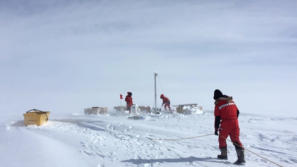 추위에 노출이 된 상태에서 빙하 시추 작업을 하고 있는 탐사팀
