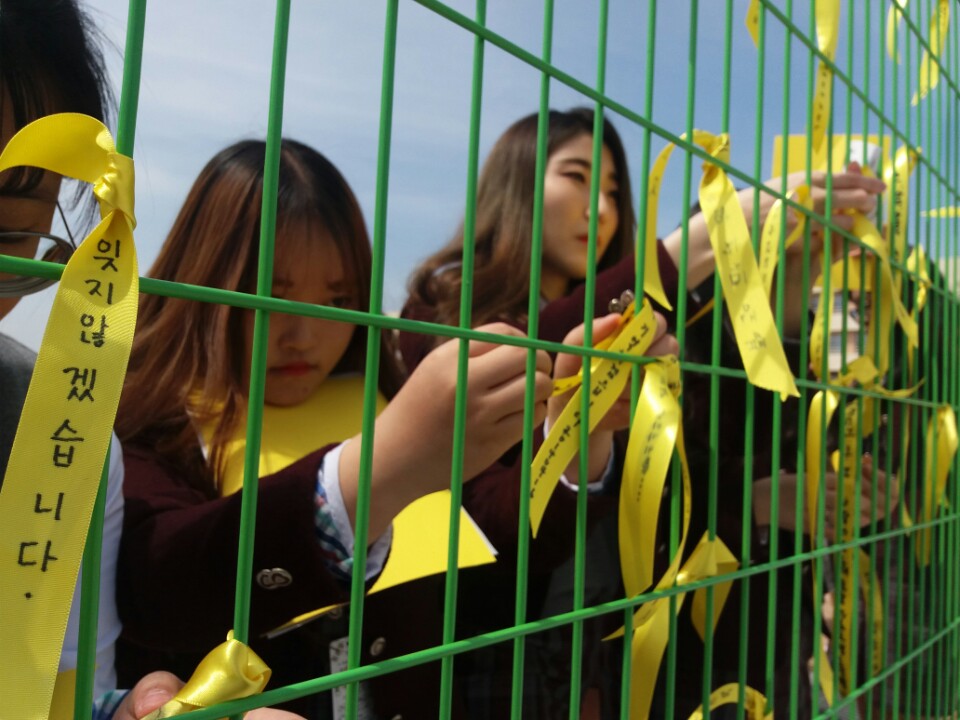지난 16일 세월호 참사 4주기 추모 플래시몹이 열린 홍성여고에서 학생들이 교내 울타리에 추모글을 적은 노란리본을 매달고 있다