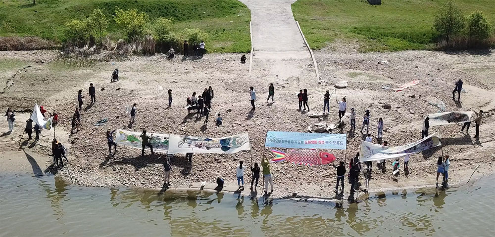 콘크리트에 가로막힌 공주보 상류에서 대형 물고기 그림과 깃발을 강변에 설치하고 있다.