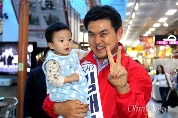 자유한국당 김태호 경남지사 후보가 24일 오후 창원 상남시장을 찾아 상인들과 인사를 나누면서 한 아이를 안고 손가락으로 브이(V)를 해보이고 있다.