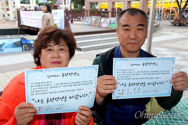 강선영(창원, 왼쪽)씨가 25일 오후 창원 상남동 분수광장에서 열린 "남북정상회담 환영 문화제"에서 '종전선언' 손팻말을 들어 보이고 있다.