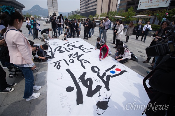  캘리그라피스트 강병인 작가가 26일 오후 서울 광화문 광장에서 남북정상회담 성공을 기원 하는 대형 붓글씨를 완성하자 시민들이 염원을 적고 있다. 