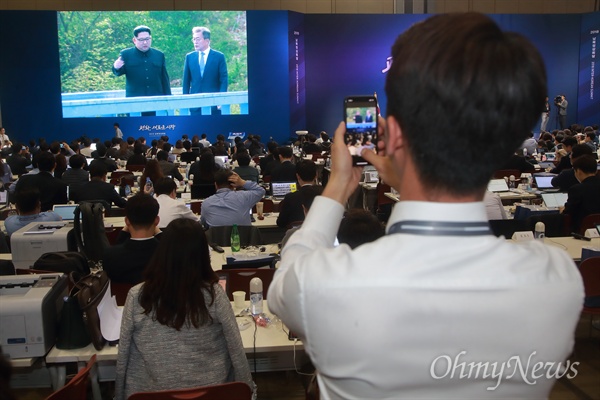 수행원 없는 단독 정상회담 지켜보는 취재기자  27일 오후 경기도 일산 킨텍스 메인프레스센터(MPC)에 마련된 대형 모니터에 문재인 대통령과 김정은 북한 국무위원장이 판문점 도보다리 산책하는 장면이 생중계되자, 취재기자가 이를 지켜보며 휴대폰으로 촬영하고 있다.