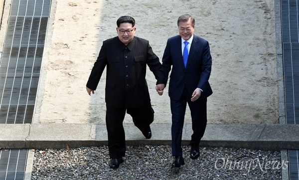 2018남북정상회담이 열린 27일 오전 문재인 대통령과 김정은 국무위원장이 손을 잡고 판문점 군사분계선을 넘고 있다.