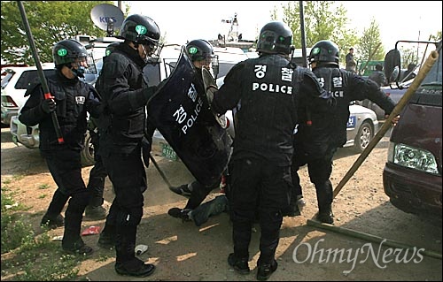 2006년 5월 4일 오전 경찰들이 대추분교에 진입하는 과정에서 여러명의 경찰들이 쓰러진 한명의 시위자를 집단구타하고 있다.