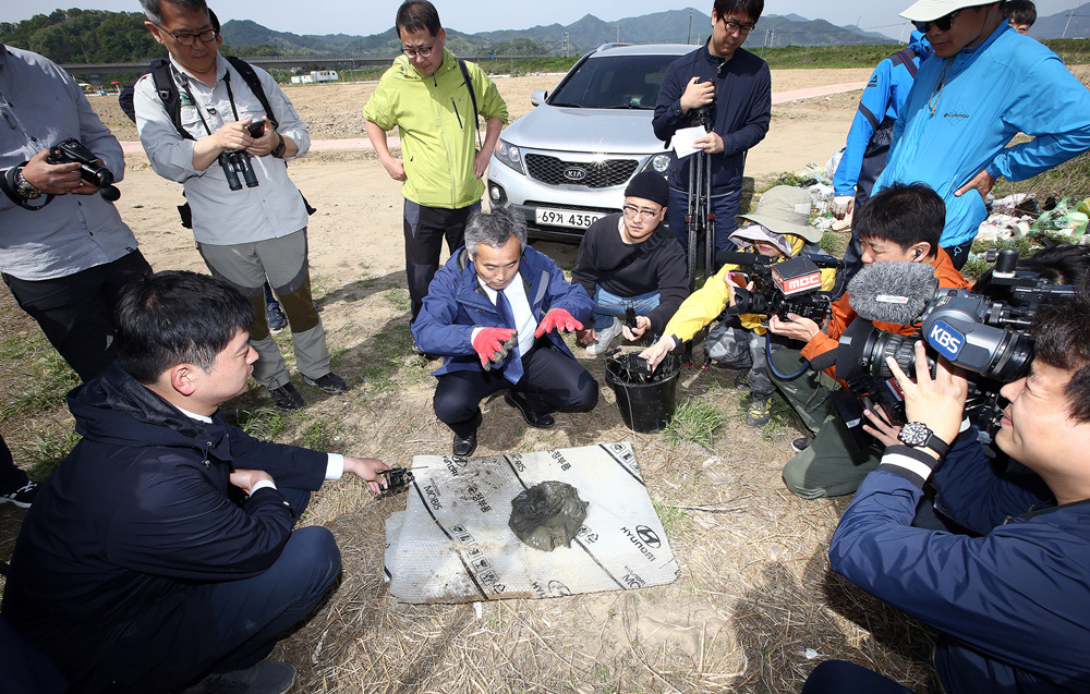 박창근 교수가 낙동강 한가운데 바닥에서 퍼온 저질토를 살펴보며 기자들에게 설명하고 있다 